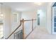 Hallway with white carpet and wooden railings, with a lovely light fixture at 3274 Heathland Way, Mount Pleasant, SC 29466