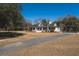 Charming white farmhouse with a long front porch and gravel driveway on a sprawling lawn at 6118 Hazelhurst Ln, Ravenel, SC 29470
