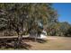 Exterior shot of a white shed underneath a tree with Spanish moss at 6118 Hazelhurst Ln, Ravenel, SC 29470