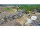 Overhead view of a rural property featuring multiple outbuildings, a gravel driveway, and a mix of fields and woods at 732 Lindhaven Dr, Pineville, SC 29468
