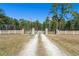 Gated entrance with flags marking a long driveway lined with white fences and a beautiful tree lined road at 732 Lindhaven Dr, Pineville, SC 29468