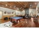 Spacious living room boasts a pool table, stone fireplace, wood paneled ceiling, and hardwood floors at 732 Lindhaven Dr, Pineville, SC 29468