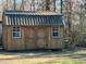 A wooden outbuilding featuring a metal roof, double doors, and white trim windows in an open backyard setting at 8072 Bing Hill Road Rd, Adams Run, SC 29426