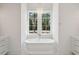 Bright bathroom featuring a standalone soaking tub beneath a chandelier and window with trees outside at 821 Bulls Bay Blvd, Mount Pleasant, SC 29429
