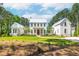 Beautiful two-story white home with a lush green lawn and a circular driveway nestled amongst mature trees at 821 Bulls Bay Blvd, Mount Pleasant, SC 29429