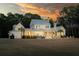 Charming home with a pool and a covered patio, set against a backdrop of mature trees at dusk at 821 Bulls Bay Blvd, Mount Pleasant, SC 29429