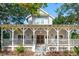 Inviting home with a spacious front porch, classic architectural details, and a beautiful yard perfect for relaxation at 94 Seaside Cottage Ln, Isle of Palms, SC 29451