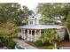 Aerial view of home with large porch, metal roof, mature trees, and a lush green yard at 94 Seaside Cottage Ln, Isle of Palms, SC 29451