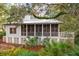Charming exterior of home with screened porch, lush landscaping, and mature trees at 94 Seaside Cottage Ln, Isle of Palms, SC 29451