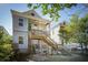 Backyard view of a two-story home featuring an exterior staircase and charming wooden porches at 318 Sumter St, Charleston, SC 29403