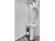 Bright powder room with pedestal sink, round mirror, and unique light fixture over hardwood floors at 1032 Berry Patch Cir, Summerville, SC 29485