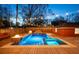 Backyard pool and spa with a fire pit, set in a wood deck and illuminated by string lights creating a luxurious retreat at 1235 Sunset Dr, Charleston, SC 29407