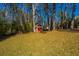 A red storage shed located in the expansive backyard amid mature trees and landscaping at 202 Hunt Club Dr, Summerville, SC 29485