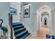 Entry staircase with blue carpet runner and a view through an arched hallway to a grandfather clock at 212 Chinaberry Ln, Kiawah Island, SC 29455