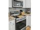 Close-up of a stainless steel oven and cooktop with a microwave above and white cabinets at 218 Mohican Cir, Summerville, SC 29483