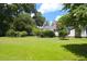 Spacious backyard featuring a lush lawn, mature trees, and the exterior of a classic white home with black shutters at 219 Rigby St, Reevesville, SC 29471