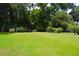 Expansive backyard with a manicured lawn, mature trees, and a charming garden shed at 219 Rigby St, Reevesville, SC 29471