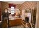 Spacious bedroom with a canopy bed, fireplace, chest, and floral wallpaper, offering a traditional aesthetic at 219 Rigby St, Reevesville, SC 29471