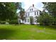 Classic white home with black shutters, surrounded by a lush green lawn and mature trees at 219 Rigby St, Reevesville, SC 29471