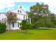 A beautiful white house stands elegantly amidst green grass and mature trees, showcasing classic charm at 219 Rigby St, Reevesville, SC 29471