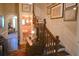 Hallway with wooden staircase and a glimpse into the vintage half-bathroom with pink tile and floral wallpaper at 219 Rigby St, Reevesville, SC 29471