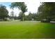 Expansive front lawn surrounded by mature trees on a sunny day in a residential area at 219 Rigby St, Reevesville, SC 29471