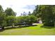 Well-maintained lawn with lush greenery, mature trees, and a view of the white home showcasing its charming curb appeal at 219 Rigby St, Reevesville, SC 29471