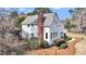 Exterior view of a white two-story home with brick chimney and lush, landscaped grounds at 2224 Shoreline Dr, Johns Island, SC 29455