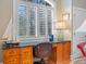 Desk area featuring wooden cabinets, stone countertop, and a window with plantation shutters at 2515 Cat Tail Pond Rd, Seabrook Island, SC 29455