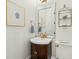 Charming powder room with decorative mirror, pedestal sink, and elegant gold fixtures at 3 Cross Ln, Isle of Palms, SC 29451