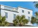 Coastal home with balcony, white trim, and palm trees against a clear blue sky at 3 Cross Ln, Isle of Palms, SC 29451