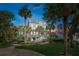 Coastal home features manicured lawn, mature palms, white railings, and water feature at 3 Cross Ln, Isle of Palms, SC 29451