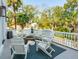 Charming outdoor balcony featuring white Adirondack chairs arranged around a fire pit, surrounded by lush trees at 3 Cross Ln, Isle of Palms, SC 29451