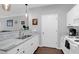 Well-lit kitchen includes white cabinetry, stainless sink, and breakfast bar with open access to the living area at 300 Bucksley Ln # 104, Charleston, SC 29492