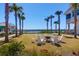Inviting lawn area with a fire pit and comfortable seating, surrounded by palm trees and a scenic waterfront view at 3034 Bell Cv Aly, Johns Island, SC 29455
