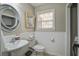 Well-lit half-bath with a pedestal sink, round mirror, modern toilet, and wainscoting at 309 Edinburgh St, Summerville, SC 29483