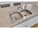 Close-up of a stainless steel kitchen sink, set in light countertops, with a modern faucet and white cabinets at 446 White Scallop Way, Summerville, SC 29486