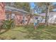 Cozy backyard featuring a brick home, wooden swing set, and lush greenery, perfect for outdoor relaxation at 886 Piccadilly Cir, Charleston, SC 29412