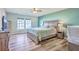 The primary bedroom has a large bed, two windows, and beautiful green accent walls at 9988 Winged Elm St, Ladson, SC 29456