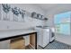 Well-lit laundry room with front-load machines, countertop, shelving, and window at 107 Willett Ln, Summerville, SC 29486