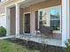 Close-up view of the cozy front porch with a wicker bench, well-defined columns and the house number above the door at 1309 Belgian Draft Dr, Mount Pleasant, SC 29466