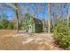 Charming, green shed with a white-trimmed door and window, nestled in a wooded backyard at 146 Picard Dr, Ladson, SC 29456