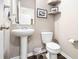 Well-lit powder room featuring a pedestal sink, toilet, and decorative shelves at 1587 Bluewater Way, Charleston, SC 29414