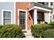 Close-up of a stylish front door with a modern light fixture, set amongst neatly trimmed hedges at 1587 Bluewater Way, Charleston, SC 29414
