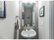 Compact powder room with pedestal sink, mirror, and neutral color scheme at 1587 Bluewater Way, Charleston, SC 29414