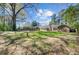 Lush green backyard, partially shaded by mature trees, with brick home in the distance at 159 Foxborough Rd, Goose Creek, SC 29445