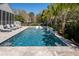 Backyard pool featuring travertine decking, lush landscaping, lounge chairs, and serene waterfall at 171 Cartright St, Charleston, SC 29492
