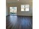 A naturally lit living room featuring gray wood floors, large windows, and sliding glass doors to outside at 1903 Scarlett Maple St, Summerville, SC 29486