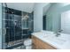 Modern bathroom with dark tiled shower, glass doors, wood cabinets, white countertop, and light fixtures at 2415 Jasper Patterson Dr, Johns Island, SC 29455