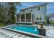 Backyard oasis featuring a modern pool with waterfall, screened-in porch, and elegant tiled patio at 2415 Jasper Patterson Dr, Johns Island, SC 29455